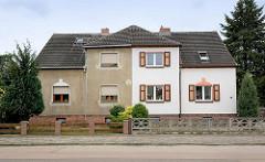 Architektur in Oranienbaum - Doppelhaus mit unterschiedlicher Fassadengestaltung - grauer Putz und weisse Hausfassade mit Fensterluken.