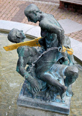 Marktbrunnen am Marktplatz von Aken / Elbe; Figurengruppe Symbol für die Zeit; Sockelinschrift: Die Zeit machte tiefe Einschnitte in unsere Stadt-vom Stadtbrand bis zur Treuhand - doch Bürgerfleiß schloss die Wunden wieder.