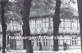 historische Aufnahme von alten Gasthof Stadt Hamburg ca. 1936 - hohe Linden stehen an der Strasse, Passanten gehen auf dem Bürgersteig oder schieben ihr Fahrrad vor dem Fachwerkgebäude. Das ca. 1550 errichtete Gasthaus hat aufwändige Schnitzerein