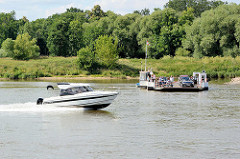 Ein Motorboot in schneller Gleitfahrt passiert die Gierfähre auf der Elbe bei Aken.