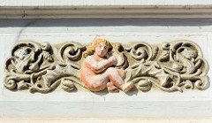 Stuckdekor an einer Hausfassade in Bad Oldesloe - Rankwerk und nackte Frau / Hafenspielerin.