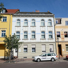 Jugendstil Mietshaus mit floralem Fassadenschmuck; weisse Ziegel mit blauen Zierbändern.