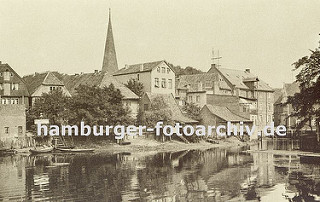 Historisches Foto aus Bergedorf ca. 1890 - Blick über den Hafen, alte Häuser stehen am Wasser, einige Boote liegen am Ufer. In der Bildmitte der Kirchturm der Bergedorfer St. Petris und Pauli Kirche. Rechts die Rückseite der Kornwassermühle mit d