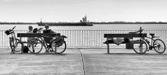 Blick auf die Elbe bei Brunsbüttel - Fahrradfahrer rasten auf ihrer Tour entlang der Elbe - ein Tankschiff fährt Richtung Brunsbüttler Schleuse.