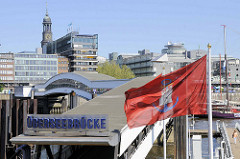 Blick auf die Überseebrücke - Fahne vom Hamburger Hafen -  Hafenflagge / Admiralitätsflagge im Wind; im Hintergrund der Kirchturm der St. Michaeliskirche und Teile vom Verlagsgebäude Gruner + Jahr am Baumwall.