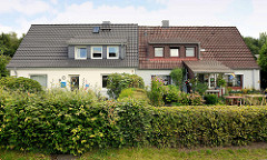 Doppelhaus mit unterschiedlich sanierter Fassade / Dach - Hecken; Architektur in der Stadt Norderstedt.
