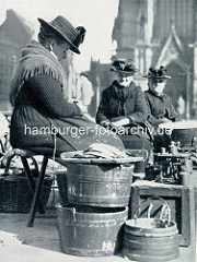 Marktfrauen / Fischverkäuferinnen auf dem Hopfenmarkt vor der Hamburger Nikolaikirche; Waage mit Gewichten.