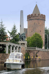 Ein Motorboot liegt vor der Stadtschleuse von Brandenburg an der Havel - im Hintergrund das Sowjetische Ehrenmal und der Steintorturm als Teil der ehem. Stadtmauer.