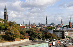 Türme der Hansestadt Hamburg; lks. die St. Michaeliskirche - re. die Schwedische Gustaf Adolfskirche; ein Zug der Hochbahn verlässt die Haltestelle Landungsbrücken.