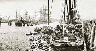 Arbeit im Hafen Hamburgs - altes Bild aus dem Hansahafen; ein Frachter wird über Schuten / Binnenschiffe  be- oder entladen.