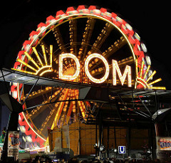 Beleuchteter Schriftzug Dom über dem Eingang am Holstenglacis - Riesenrad in Bewegung, Langzeitaufnahme.