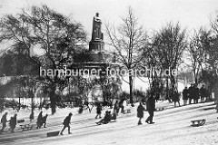 Alte Fotografie von Hamburg im Winter - Kinder rodeln am Alten Elbpark, im Hintergrund das Bismarckdenkmal.