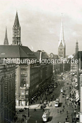 Historische Fotografie von der Mönckebergstraße in der Hamburg Innenstadt / Altstadt; Straßenbahnen, PKW und Fahrradfahrer. Lks. der Kirchturm der St. Jakobikirche und St. Nikolai - re. die Petrikirche und der Hamburger Michel.