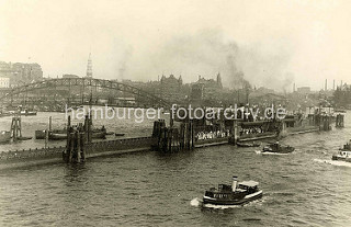 Ponton mit wartenden Fahrgästen an der Überseebrücke; Barkassen und Tuckerboot in Fahrt - im Hintergrund die Hamburger Speicherstadt und die Einfahrt zum Sandtorhafen.