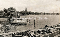 Alte Fotografie - Ufer mit Bootssteg und Booten am Ruppiner See. Kirchtürme der Klosterkirche St. Trinitatis von Neuruppin.