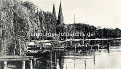 Historische Ansicht - Ufer mit Bootssteg und Segelbooten am Ruppiner See. Kirchtürme der Klosterkirche St. Trinitatis von Neuruppin.