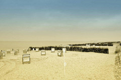Strand mit leeren, verschlossenen Strandkörben - Nordseestrand in Duhnen / Cuxhaven - in Sand gesteckte Reisigbesen als Windschutz.