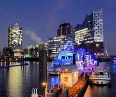 Blick über den Jonashafen / Sportboothafen zum Bürogebäude am Kehrwieder und der  Elbphilharmonie in der Hamburger Hafencity - im Vordergrund blau beleuchtete Fahrgastschiffe der Hamburger Hafenrundfahrt.