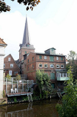 Wohnhäuser und Speicher am Ufer der Medem in Otterndorf - Kirchturm der St. Severi Kirche.