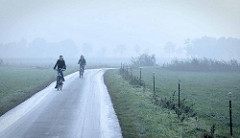 Radausflug im Herbst - Radfahrer / Radfahrerin auf einem Feldweg im Nebel bei Otterndorf  am Liebesweg / Zutrifft.