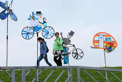 Windspiele am Deich - Skelett auf Fahrrad mit drehenden Rädern - bunter Wohnwagen; Souvenirverkauf in Duhnen / Cuxhaven.
