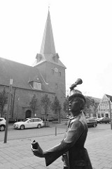 Skulptur der Utröper / Ausrufer, Bildhauer Frijo Müller-Belecke am Kirchplatz in Otterndorf - im Hintergrund die St. Severi Kirche.