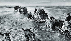Historische Ansicht von Wattwagen im Wasser - Personenwagen mit Touristen von Pferden gezogen auf den Weg zur Insel Neuwerk.