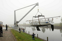 Am Hadelner Kanal wird in Otterndorf ein Segelschiff gekrant, mit einem Kran für das Winterlager an Land gehievt.