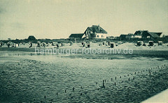 Nordseestrand mit Strandkörben und Ferienhäuser am Deich beim Nordseebad Duhnen.