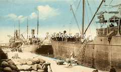 Alte colorierte Fotografie vom Hafen in Tunis / Tunesien - Dampfschiffe / Frachter; angelehnte Holzleitern - gestapelte Säcke auf dem Kai.