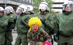 Clandestine Insurgent Rebel Clown Army / CIRCA; Heimliche Aufständische Rebellen-Clownarmee: Clown Demonstranten bei der Arbeit - Polizisten schauen zu.
