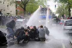Die friedliche Straßenblockade durch Demonstranten wird von der Hamburger Polizei durch den Einsatz eines Wasserwerfers aufgelöst.