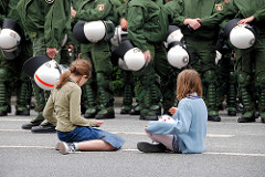 Ruhe vor dem Sturm - Mädchen sitzen auf der Straße, die Polizeimanschaften sammeln sich. Demonstation am Millerntor in Hamburg St. Pauli.