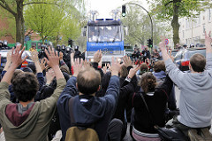 Friedliche Blockade einer Straße durch Demonstranten, die ihre Hände hochhalten - Hamburger Polizisten in Kampfmontur und Wasserwerfer.
