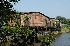 Blick über den Veddeler Marktkanal zu einem historischen Lagerhaus am Ufer des Kanals. Ein Steg und Eisendalben ermöglichten ein Anlegen von Schiffen.