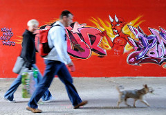 Fussgänger mit Hund unterqueren die Wilhelmsburger Reichsstrasse im Fußgängertunnel - an der Mauer ist ein Graffiti mit Teufel angesprüht.
