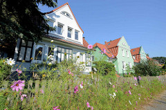 Bunte Straßenblumen im Resedenweg in Hamburg Fuhlsbüttel - schmucke Einzelhäuser mit Holzluken  und farbiger Fassade.