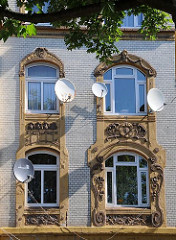 Die Fenster des Wohnhauses in der Wilhelmsburger Strasse Vogelhüttendeich sind mit farblich abgesetzten Jugendstil- Dekoren eingefasst.