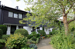 Reihenhäuser mit dunkler Schieferfassade und dicht bewachsen im Vorgarten - Architekturbilder  aus Hamburg Hummelsbüttel.