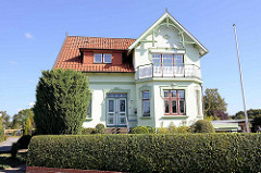 Ländliche Villa aus der Gründerzeit  mit farblich abgesetztem Stuckdekor um Fenster und Türen; Ziergiebel aus Holz.
