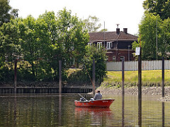 Ein Angler ankert mit seinem kleinen Motorboot vor dem Hafen der Bunthäuser Stackmeisterei - er hat zwei Angeln in das auflaufende Wasser der Norderelbe geworfen.