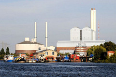 Am Ufer von Kaltehofe in der Billwerder Bucht liegen an einem Anleger Barkassen und Hausboote. Die Abendsonne bescheint das Kraftwerk Tiefstack.