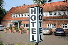 Leuchtreklame Hotel am Straßenrand - lang gestrecktes Gebäude mit mehrteiliger Fenstergaube.