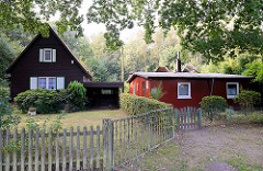 Holzhaus mit Spitzdach  und Fensterläden mit Carport  und Holzzaun / flaches, schlichtes Holzhaus.