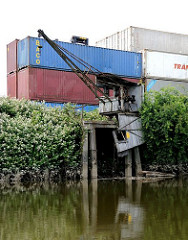 Containerlager mit leeren Containern am Ufer des Schmidtkanals - alter, verrotteter Hafenkran.