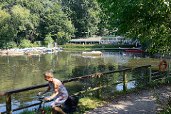 Bootsverleih am Mühlenteich / Alster in Hamburg Fuhlsbüttel - Gartenrestaurant, Café. Im Vordergrund eine Fahrradfahrerin auf dem Alsterwanderweg.