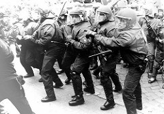 Polizisten in Kampfmontur zeigen Interesse an den Demonstranten, freundlich bereiten sie sich auf die nonverbale Kommunikation vor / Polizeieinsatz  Hamburg.