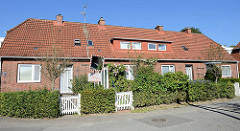 Siedlungsreihenhaus der 1930er Jahre in der Rotdornallee in Hamburg Bramfeld. Eingänge für drei Wohneinheiten und kleinem Vorgarten.