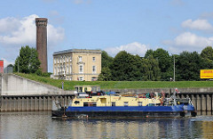 Ein Schubschiff fährt auf der Billwerder Bucht Richtung Sperrwerk zur Elbe. Im Hintergrund der Turm der Wasserkunst von den Wasserwerken Rothenburgsort.