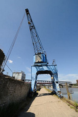 Der blaue Hafenkran am Billhafen in Hamburg Rothenburgsort wird auf Schienen entlang der Kaianlage bewegt.